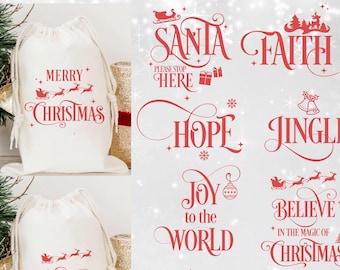 Op de afbeelding: Een witte stoffen tas met trekkoord, voorzien van rode tekst en afbeeldingen zoals Merry Christmas, Santa Please Stop Here, Faith, Hope, Jingle, Joy to the World en Believe in the Magic of Christmas, inclusief rendier- en ornamenticonen.