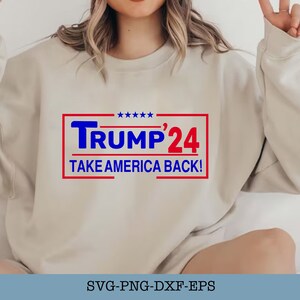 Könnte beinhalten: Ein weißer Pullover mit einer roten und blauen Grafik, auf der "TRUMP'24 TAKE AMERICA BACK!" steht.