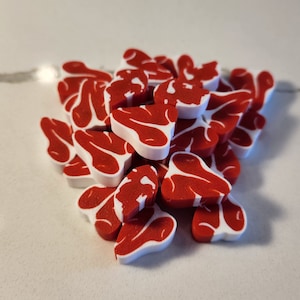 May include: A pile of red and white plastic steak shaped game pieces.