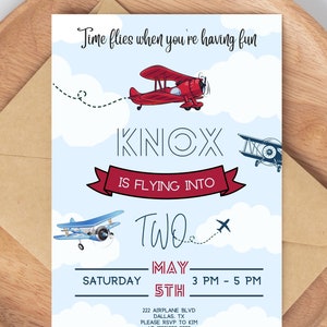 Könnte beinhalten: Eine blaue und weiße Einladung zum Thema Flugzeug für den zweiten Geburtstag eines Kindes. Die Einladung zeigt ein rotes Flugzeug, das durch die Wolken fliegt, mit dem Text "Knox is flying into two" und "May 5th, 3 PM - 5 PM".