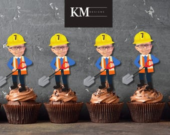 May include: Four yellow construction worker themed cupcakes with a yellow hard hat, blue shirt, and a shovel. Each cupcake has a number 7 on the hat.