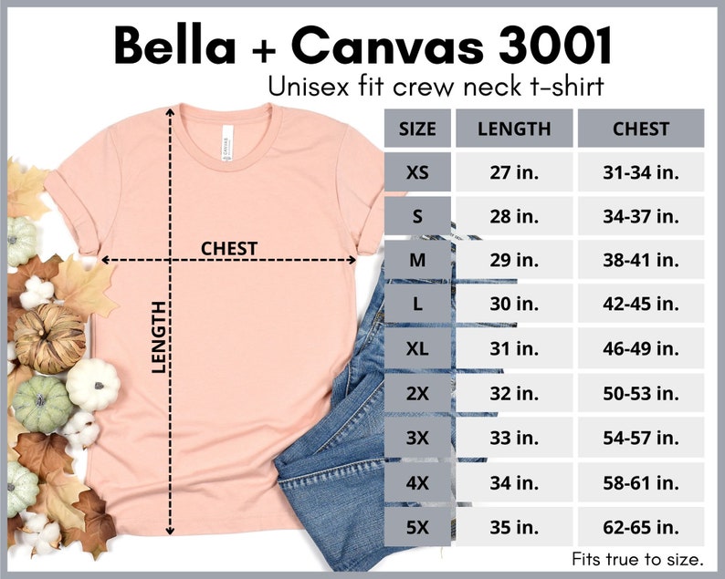 May include: A light peach-coloured Bella + Canvas 3001 unisex fit crew neck t-shirt. The image includes a size chart with measurements in inches for chest and length, ranging from XS to 5X. The shirt is displayed with a pair of blue jeans and autumn-themed decorations.