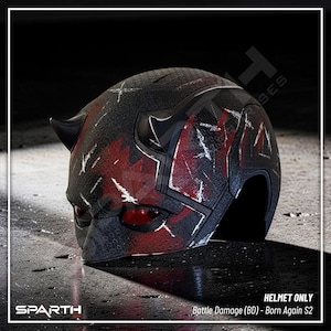Puede incluir: Un casco negro y rojo con una superficie texturizada, con un diseño dañado por la batalla. El casco tiene dos cuernos negros y lentes oculares rojas. El texto "SPARTH" es visible en la parte inferior izquierda. El texto "Battle Damage (BD) - Born Again S2" también es visible.