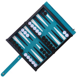 May include: A black and white backgammon board with black and white playing pieces. The board is folded and has a blue felt surface. The board is open and ready to play.