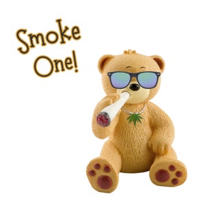 May include: A tan teddy bear figurine wearing sunglasses and a necklace with a marijuana leaf pendant. The bear is holding a lit joint in its mouth. The text "Smoke One!" is in the upper left corner.