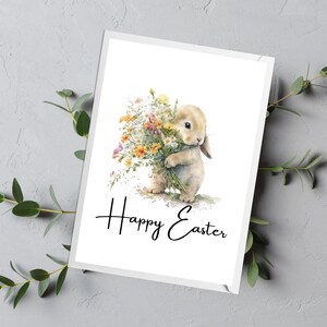 May include: A white bunny holding a bouquet of yellow, orange, and white flowers. The bunny is standing on a white background with the text "Happy Easter" written below it.