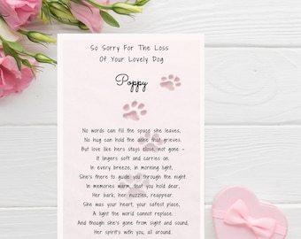 May include: A sympathy card with the text "So Sorry For The Loss Of Your Lovely Dog Poppy" and a poem. The card has paw prints and is surrounded by pink flowers and a heart-shaped gift box with a bow.
