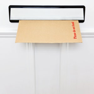 May include: A brown envelope with the words "Please do not bend" printed in red on the right side is sticking out of a silver mailbox.