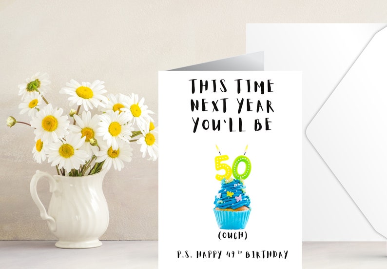 May include: A birthday card with a blue cupcake with green and yellow candles that say "50". The card says "This time next year you'll be 50 (ouch) P.S. Happy 49th Birthday"