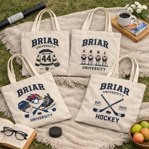 Op de afbeelding: Vier off-white canvas draagtassen met Briar University ijshockeyontwerpen. Eén toont een shirt met nummer 44, een andere vier ijshockeyers, één een helm en schaats, en de laatste gekruiste ijshockeysticks met bijbehorende tekst.