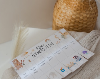 May include: A white card with the text "Meine Abendroutine" printed on it. The card is divided into sections with illustrations of a toilet, bath, pajamas, toothbrush, book, and a child sleeping. The card is on a white blanket.