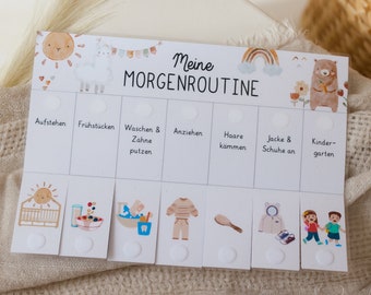 May include: A white board with a colorful illustration of a sun, a llama, a rainbow, and a bear. The board is divided into sections with the text "Meine MORGENROUTINE" at the top. Each section has a title and an image, such as "Aufstehen", "Frühstücken", "Waschen & Zähne putzen", "Anziehen", "Haare kämmen", "Jacke & Schuhe an", and "Kinder-garten".