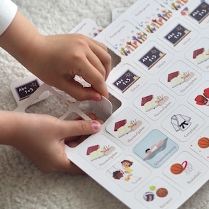 May include: A white board game with colorful illustrations and text in German. The game features cards with images of activities like school, swimming, and sports. The text on the cards includes "Abc 1+3", "Schule", "Hausaufgaben", "Schwimmtraining", "Kampfsport", "Turnen", "Ballsport", and "Basketball".