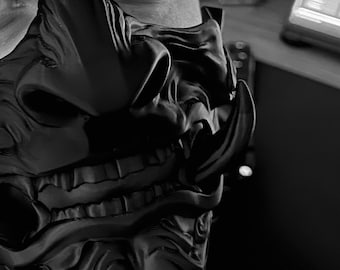 May include: A black and gray 3D printed mask with a detailed design of a Japanese demon face.