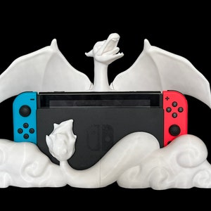 May include: White 3D printed dragon figurine with wings outstretched, holding a Nintendo Switch console in its claws. The dragon is perched on a cloud-shaped base.