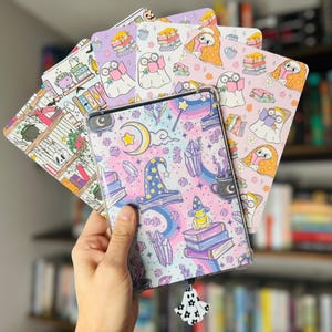 Puede incluir: Una colección de seis fundas de teléfono coloridas con diferentes diseños caprichosos. Las fundas están todas decoradas con lindas ilustraciones de fantasmas, libros y otros elementos mágicos. Las fundas están todas hechas de un material plástico duradero y son perfectas para proteger tu teléfono de arañazos y golpes.