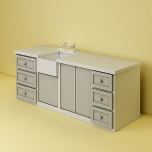 May include: A white porcelain farmhouse sink with two chrome faucets is installed in a gray cabinet with multiple drawers. The cabinet is made of wood and has a white countertop.