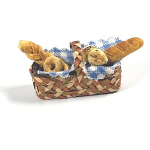 May include: A small woven basket with a blue and white checkered cloth lining. The basket is filled with bread, including a baguette and a braided loaf.