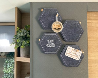 May include: A gray felt hexagon wall decor with the text "Home on Wheels" and a small wooden camper trailer cutout. There is a second hexagon with the text "Home Decor on Wheels" and a third hexagon with a wooden camper trailer cutout.