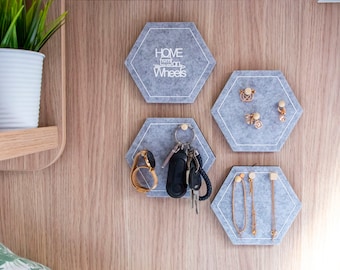 May include: Four gray hexagonal felt pads with white text and images. The top pad says "Home on Wheels". The pad below it has a watch and keys. The pad to the right of the top pad has earrings. The pad to the right of the middle pad has necklaces.
