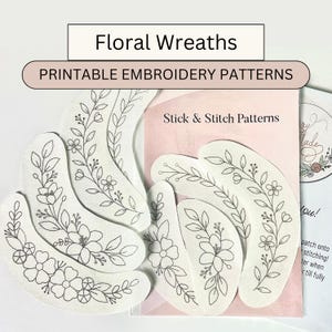 以下が含まれることがあります： フローラルリース刺繍パターン。画像には、黒い糸で花柄のデザインが施された、いくつかの白い湾曲したパッチが表示されています。「Floral Wreaths」と「Printable Embroidery Patterns」の文字が見えます。
