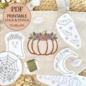 以下が含まれることがあります： ハロウィーンをテーマにした刺繍テンプレートが多数入ったベージュのトートバッグ。テンプレートには、カボチャ、幽霊、クモの巣、コウモリ、三日月が含まれています。「PDF Printable Stick & Stitch Template」の文字が上部の円に表示されています。