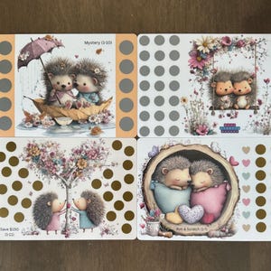 May include: Four illustrated cards featuring hedgehogs. One shows hedgehogs in a boat under an umbrella, another with floral accents, a third with a tree, and the last inside a log. Each card has a different design and text.