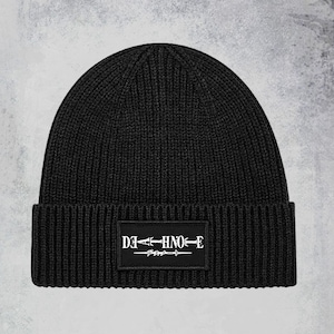 May include: Black knitted beanie with a black patch featuring the text "DEATH NOTE" in white with a stylised sword design.