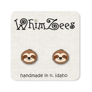 May include: A pair of brown sloth stud earrings with a white background. The earrings are handmade in Idaho and feature the text "WhimZeEs" with a daisy.