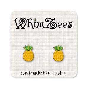 May include: A pair of small, yellow pineapple earrings with green leaves. The earrings are handmade in Idaho and are sold by the company WhimsZeEs.