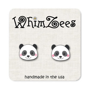 May include: A pair of panda bear stud earrings with black ears, black eyes, and pink cheeks. The earrings are on a white background with the text "Whimzees" and "handmade in the USA".