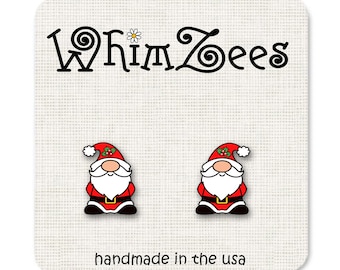 May include: A pair of red and white Christmas gnome earrings with a white beard and black eyes. The earrings are handmade in the USA and feature the text "Whimzees".