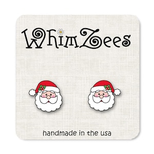 May include: A pair of Santa Claus earrings with red hats, white beards, and black eyes. The earrings are handmade in the USA and feature the text "Whimzees".
