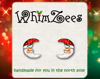 May include: A pair of red and white crescent moon earrings with a sleeping Santa face on each. The earrings are handmade and have the text "Whimzees" and "handmade for you in the north pole" on the card.