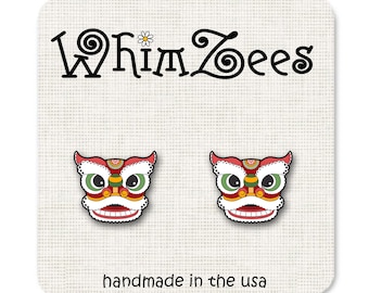 May include: A pair of red, white, and green lion dance earrings with a whimsical design. The earrings are handmade in the USA and feature a whimsical design.