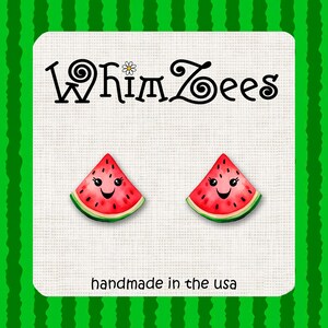 May include: A pair of watermelon slice earrings with a smiling face. The earrings are handmade in the USA.