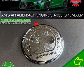 Puede incluir: Un emblema de arranque/parada del motor AMG Affalterbach plateado. El emblema tiene 37 mm de diámetro y está hecho de aluminio. El texto "AMG Affalterbach" es visible. El emblema es para Mercedes Benz.