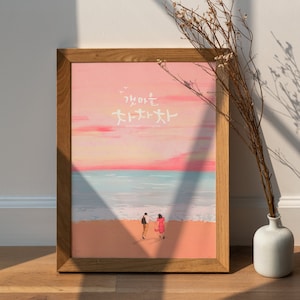 May include: A framed print of a couple walking on a beach at sunset. The sky is pink and orange, and the sea is blue. The text on the print reads "감사는  처처곳곳".