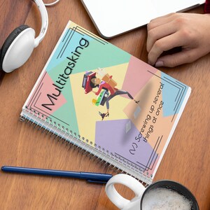 May include: A spiral bound notebook with a colorful cover featuring a woman juggling multiple tasks. The cover text reads "Multitasking (>) Screwing up several things at once".