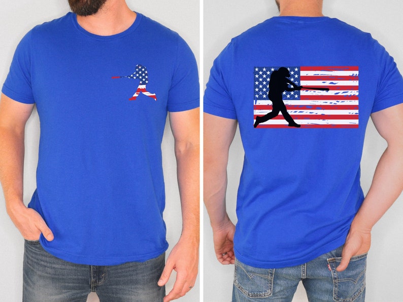 May include: A royal blue t-shirt with a baseball player silhouette in front of an American flag on the front and a baseball player silhouette in front of a distressed American flag on the back.