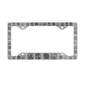May include: A silver license plate frame with a repeating pattern of black line art illustrations of a castle, a sphere, and other architectural designs. The frame has four screw holes.
