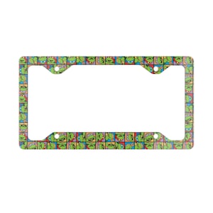 May include: A rectangular license plate frame featuring a repeating pattern of green turtle faces in colorful squares. The frame has a white center opening and mounting holes.