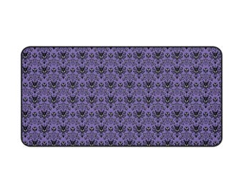 May include: Rectangular purple mousepad with a repeating black pattern of stylized gothic architectural elements and faces. The mousepad has rounded corners and a black border. The design is reminiscent of a haunted house.