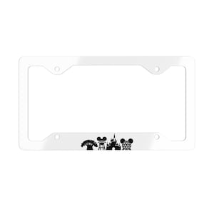 May include: White license plate frame featuring black silhouettes of a tree, film reel, castle, and Mickey Mouse head. The frame has four mounting holes and a glossy finish.