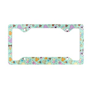 May include: A rectangular license plate frame with a light mint green background featuring a repeating pattern of colorful cartoon treats, including ice cream cones, cotton candy, donuts, and mouse-shaped snacks in shades of pink, blue, and orange.