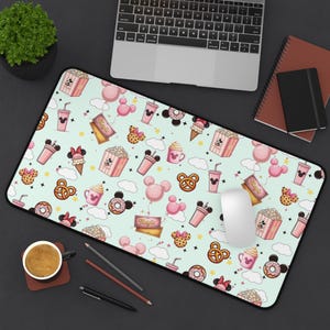 May include: A rectangular mousepad with a light green background featuring a pattern of pink Mickey Mouse-themed food and balloons. The design includes popcorn boxes, ice cream cones, and drink cups.