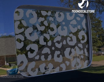 May include: A gray leopard print decal for a car window. The decal is on a black car window. The decal is a popular design for car windows and can be used to personalize a car.