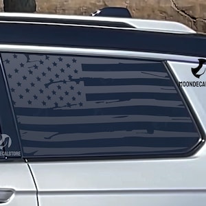 May include: A gray car with a black and white American flag decal on the rear window. The decal is distressed and has a faded look. The decal has the text "MOONDECALSTORE" on the bottom right corner.