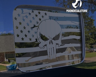 May include: A white skull graphic with a distressed American flag background. The skull has a menacing expression with a furrowed brow and a prominent jawline. The flag is faded and has a distressed look, with the stars and stripes clearly visible. The graphic is on a black background.