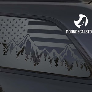 May include: A black car with a rear window decal featuring a mountain range silhouette with a US flag design. The decal is in a gray color and includes the text "MOONDECALSTORE".